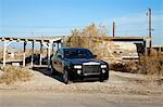 Rolls Royce parked on roadside in front of abandoned house