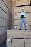 Portrait of a worker standing on stack of plywood