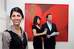 Portrait de femme jeune souriante devant un couple dans la galerie d'art
