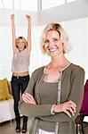Mother smiling in front of excited daughter with hands raised