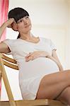 Pregnant woman sitting on chair and looking away
