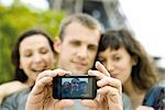 Homme lui-même photographier avec deux amis à l'aide de téléphone portable