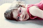 Little girl with glasses lying on side