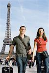 Tourist paar gehen mit ihrem Gepäck in der Nähe von Eiffelturm, Paris, Frankreich