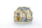 Model house folded with dollar bills chained and padlocked