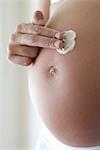Frau Anwendung Feuchtigkeitscreme zu schwangeren Bauch, zugeschnitten