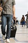 Male traveler walking with luggage, cropped