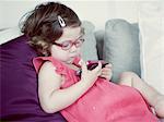 Little girl reclining on couch looking at cell phone