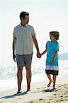 Vater und Sohn gehen Hand in Hand am Strand