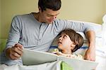 Father and son reading book together