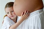 Mädchen umarmen schwangeren Bauch der Mutter