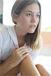 Woman touching knee, looking away in thought