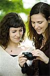 Woman showing digital camera to friend