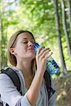 Femme buvant de l'eau embouteillée dans les bois