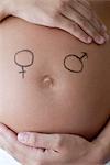 Male and female symbols drawn on woman's pregnant belly