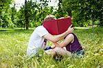 Teenagers hiding behind book in park