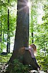 Girl hugging tree in forest