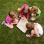 Girls making a kite in grass