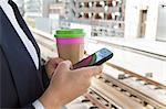 Close up of woman with coffee and smart phone in train station