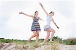 Women playing airplane on beach