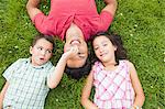Father lying on grass with son and daughter