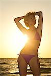 Femme à la plage silhouettée sur le coucher du soleil