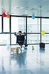 Businessman sitting in new office with balloons and box