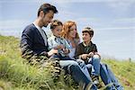 Parents and young boys sitting on meadow