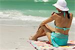 Woman at the beach, applying sunscreen