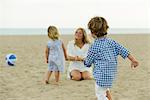 Boy playing on beach, family in background