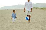 Père et fils jouer avec le ballon à la plage