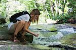 Female hiker drinking water from stream