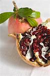 Fresh pomegranates, one cut open revealing seeds