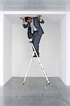 Executive standing on stepladder, pushing ceiling