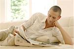 Young man reading newspaper on couch