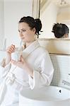 Young woman drinking coffee in bathroom