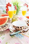 Orangensaft mit roten Johannisbeeren/Ribiseln und Wassermelone auf Tisch