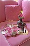 Tray with liqueur, book and candles on pink couch