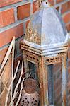 Rusty lantern in front of brick wall