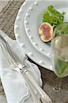 Plate with fig and lettuce leaf and glass of champagne