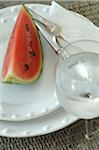 Slice of watermelon on plate and glass of water