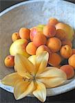 Apricots, apples and lily blossom in a bowl