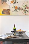 Book, red wine and fruit bowl on table
