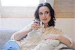 Jeune femme sur le canapé, verre d'eau à boire