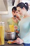 Young couple in kitchen cooking spaghetti and drinking red wine