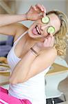 Young woman covering her eyes with cucumber slices