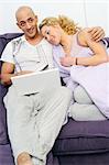 Happy couple on couch using laptop