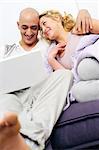 Happy couple on couch using laptop