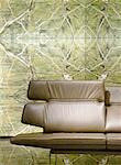Brown leather couch in front of green wallpaper