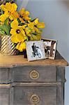 Bunch of flowers and photographs on dresser
